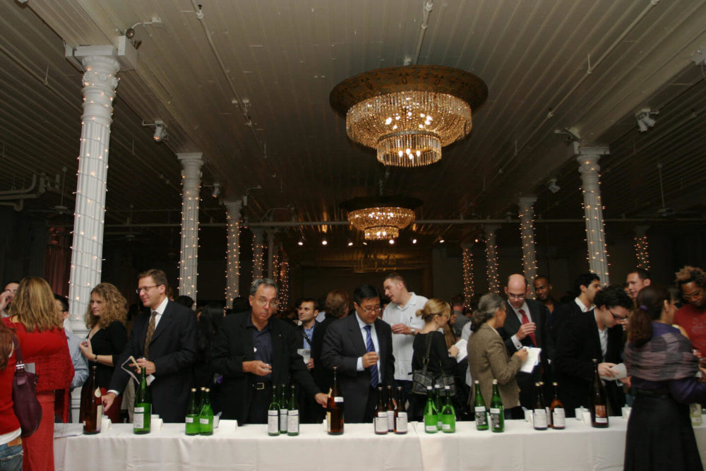 jos05ny008 Crowd of people sampling sakes on the table in a dark room (2005 New York)