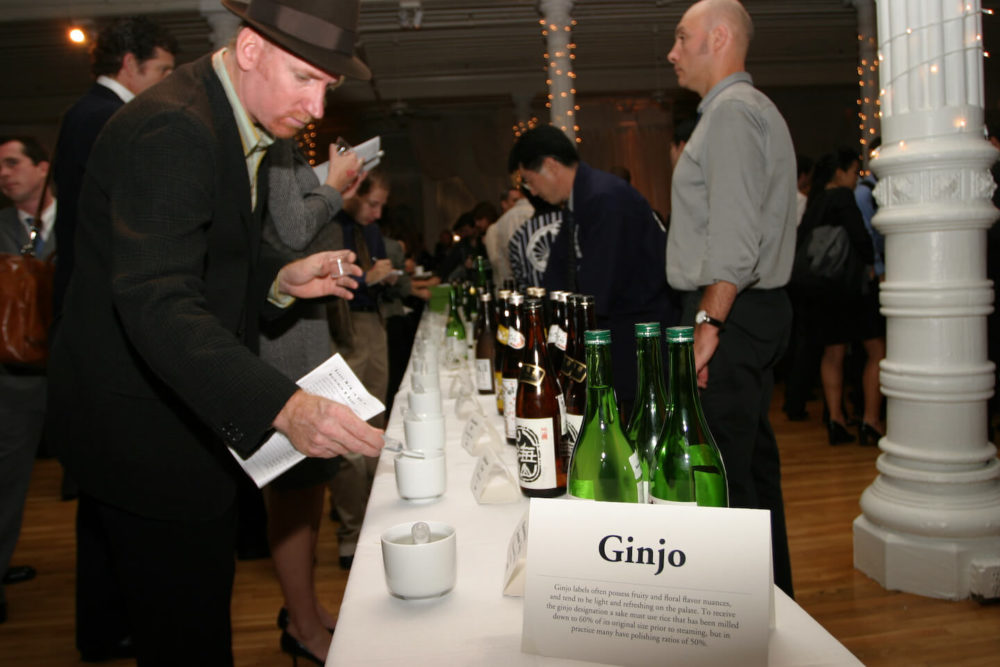 jos05ny010 A man with a hat sampling sake with a pipette at the ginjo table (2005 New York)