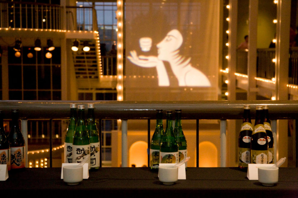 jos08sf048 Sake sampling table on the second floor across from the projected Sake Chick illustration (2008 San Francisco)